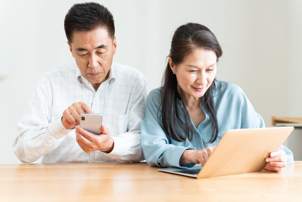 火災保険の無料診断をイメージした60代夫婦の写真。ご主人がスマホを操作し、奥さんがパソコンを見ながら相談している様子
