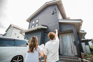 外壁塗装が終わった家を見上げる夫婦と子供
